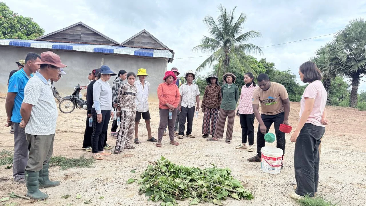 Women and men observe a farm-input preparation demonstration outdoors