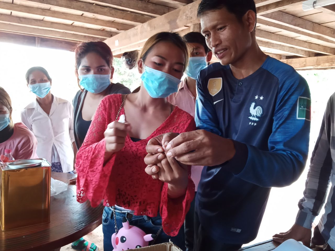 Women and a trainer practise handling a chick during practical poultry training